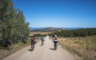 a group of people riding bikes down a dirt road
