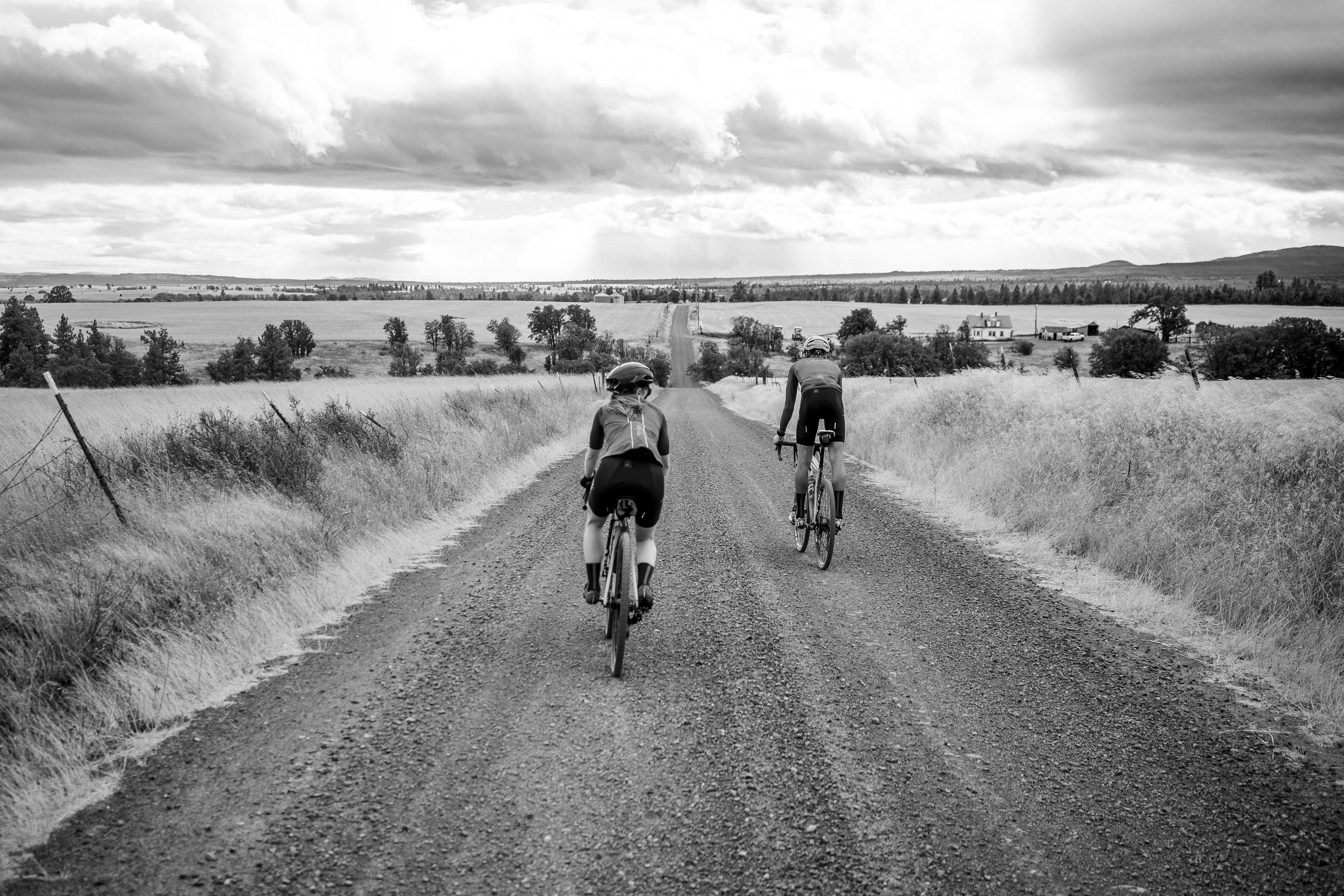 a couple of people riding bikes down a dirt road