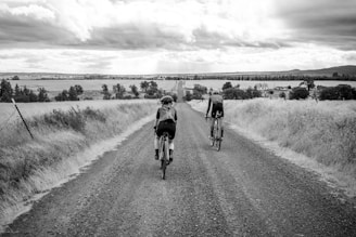 a couple of people riding bikes down a dirt road