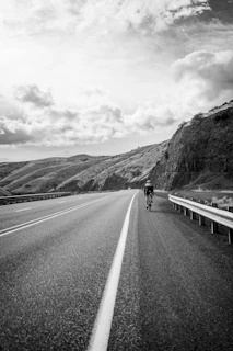 Dynamic photo of a cyclist riding a road bike on an open highway with a clear blue sky