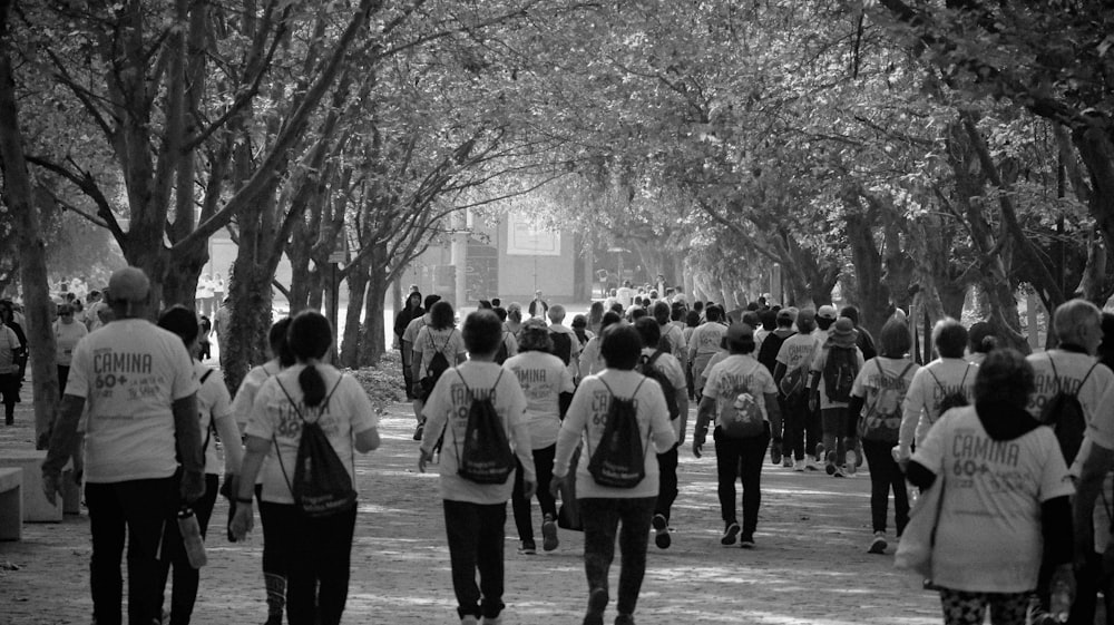 a group of people walking down a street next to trees