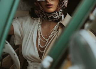 a woman wearing sunglasses and a scarf sitting in a car