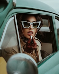 a woman in sunglasses smoking a cigarette in a car