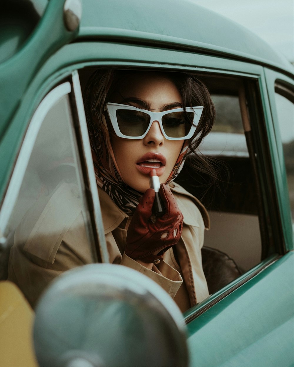 a woman in sunglasses smoking a cigarette in a car