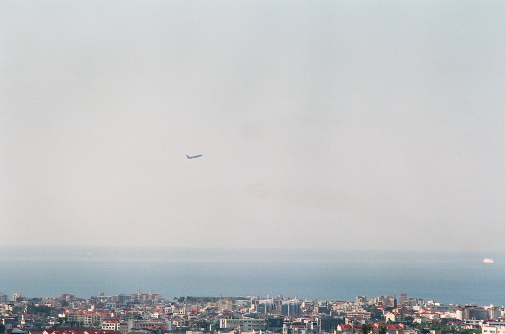a plane flying over a city with a large body of water in the background