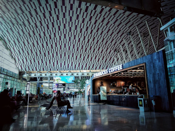 A panoramic shot of a group enjoying coffee at a cozy airport lounge, waiting for their flight.