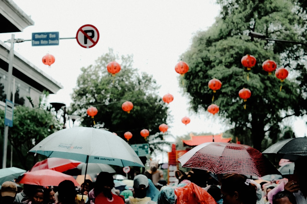 a crowd of people walking down a street holding umbrellas