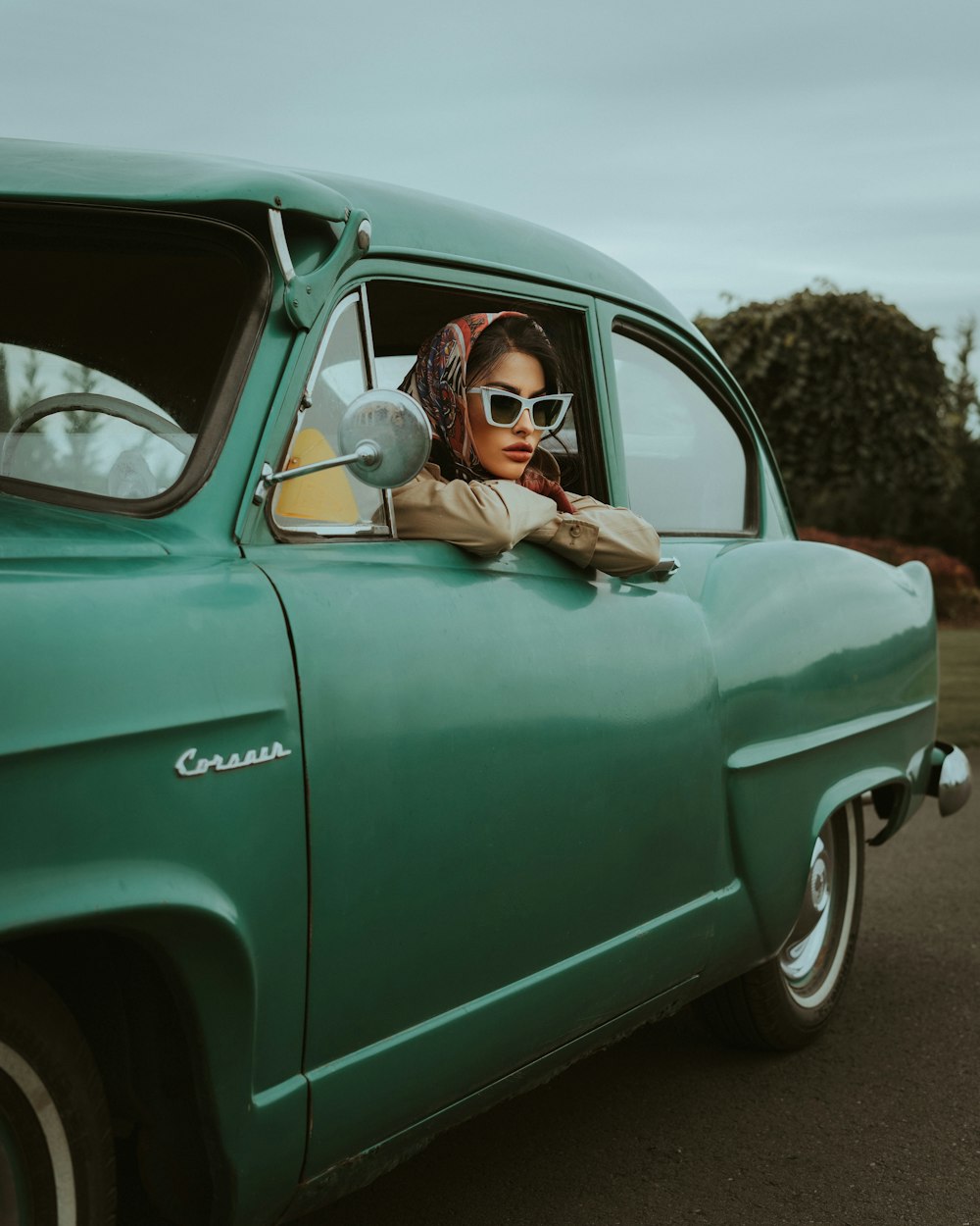 a woman sitting in the drivers seat of a green car