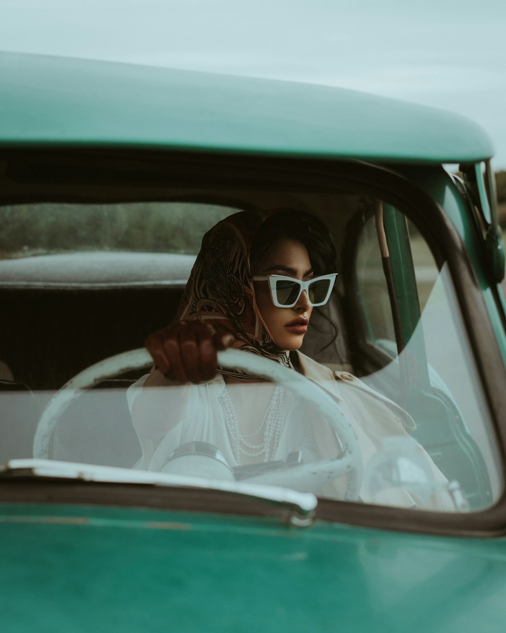 uma mulher que usa óculos de sol sentada em um carro verde