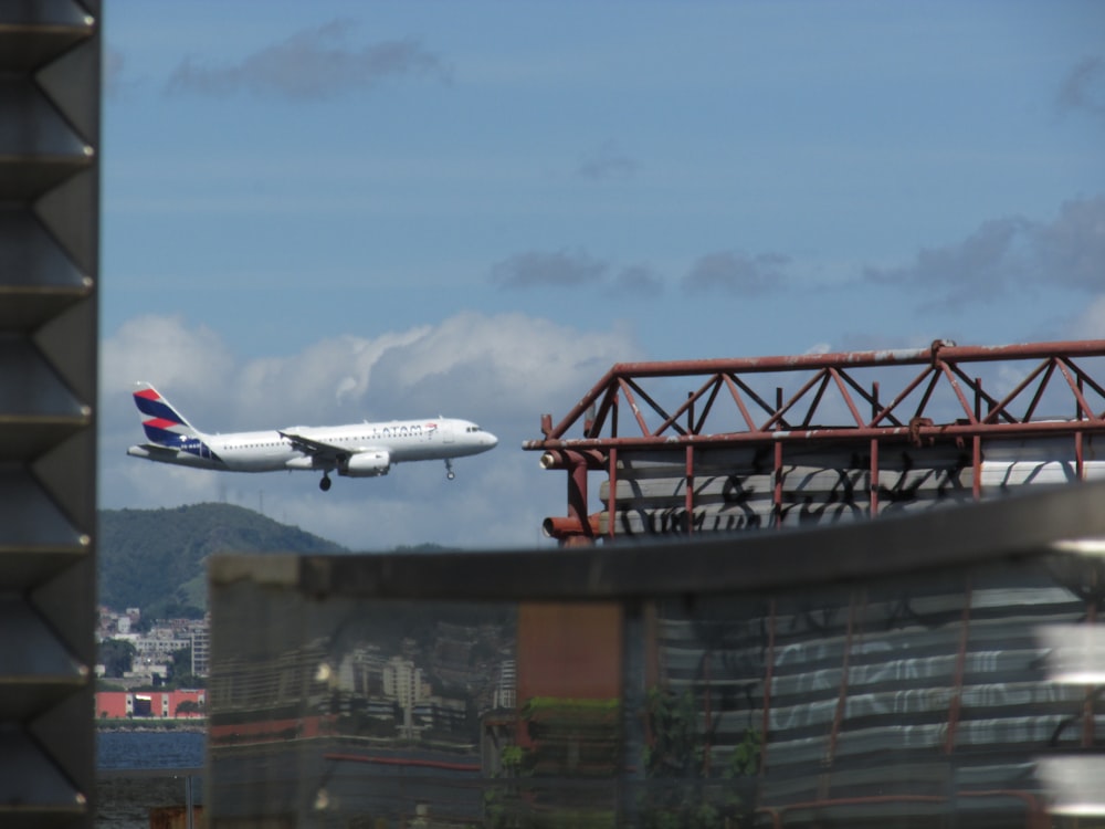 a large jetliner flying over a city under a blue sky