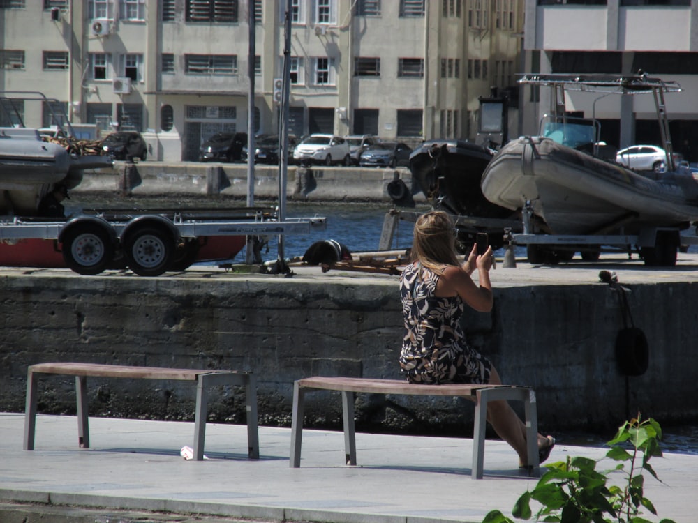 a woman sitting on a bench in front of a marina
