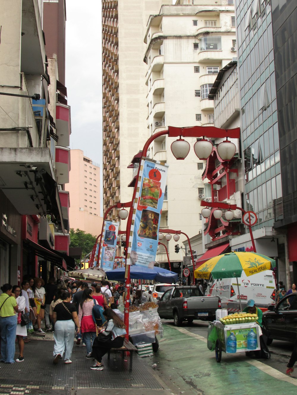 a group of people walking down a street next to tall buildings