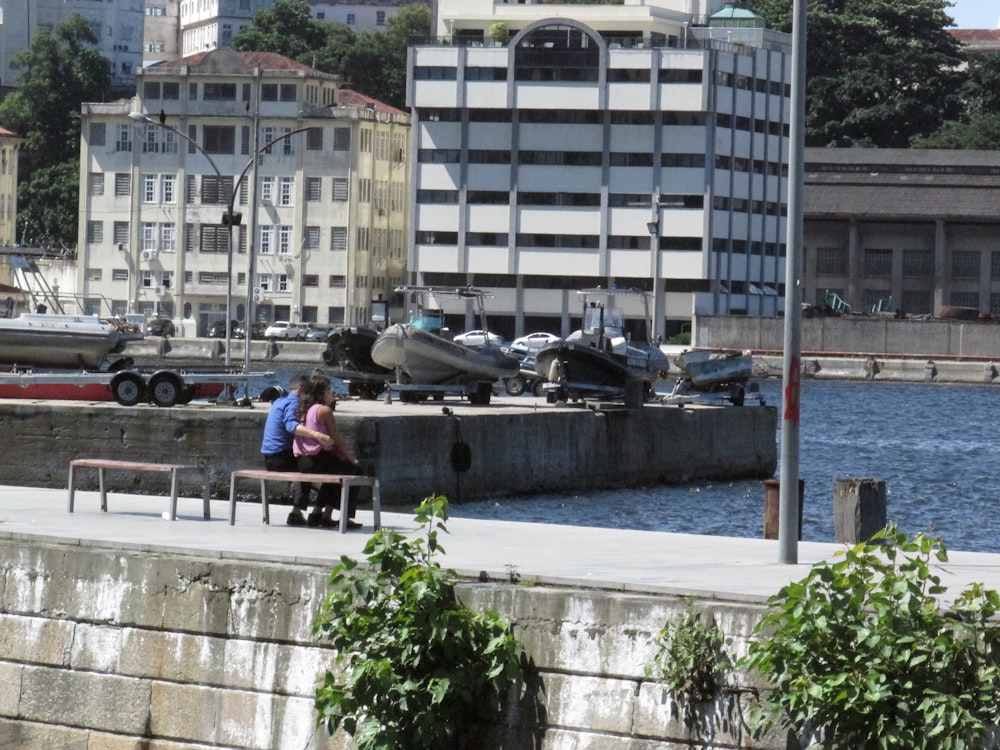 a couple of people sitting on a bench next to a body of water