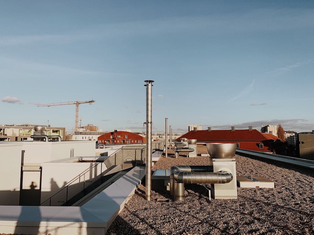 a view of a rooftop with pipes and buildings in the background