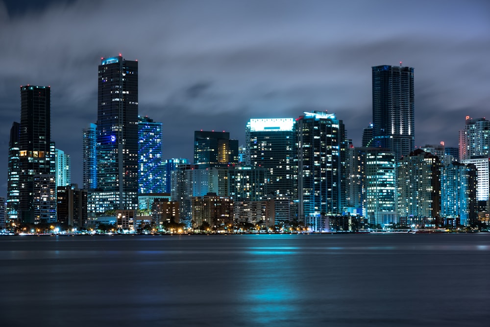 a city skyline at night with lights reflecting off the water