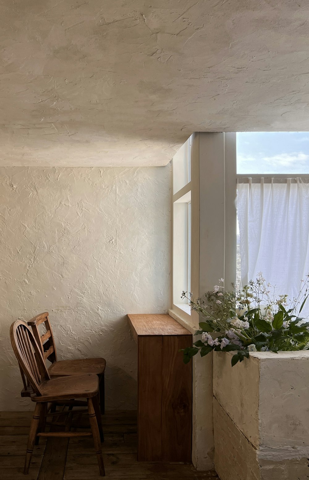 a wooden chair sitting in a room next to a window