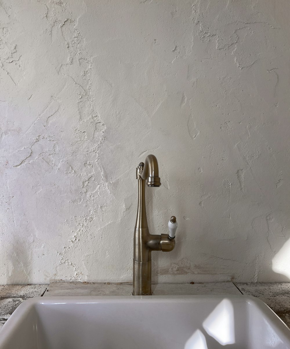 a white sink sitting next to a white wall