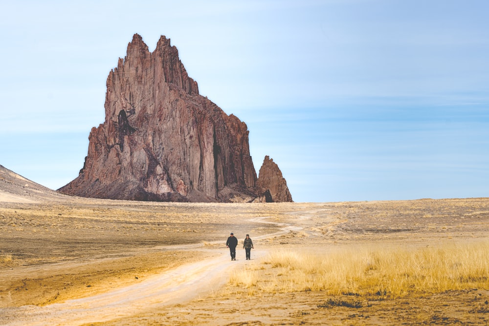 a couple of people walking down a dirt road