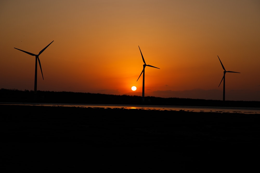a sunset with three windmills in the background