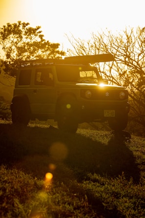 A rugged safari vehicle parked beside acacia trees under a golden sunset in Nairobi.