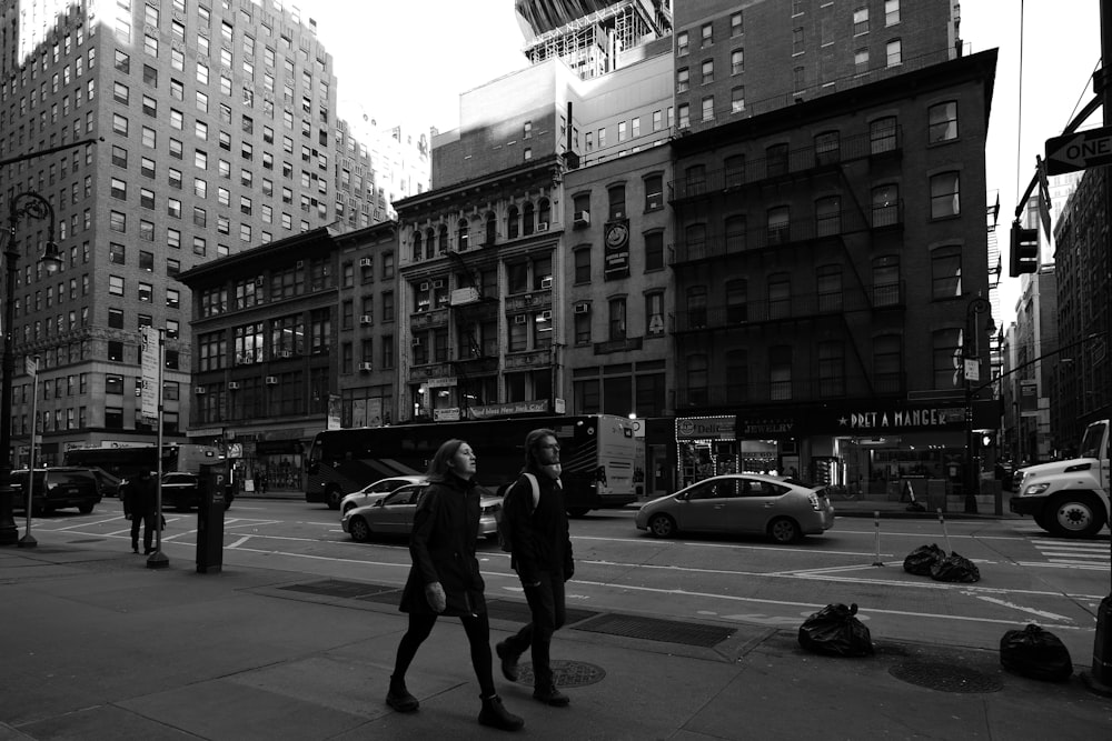 a couple of women walking down a street next to tall buildings