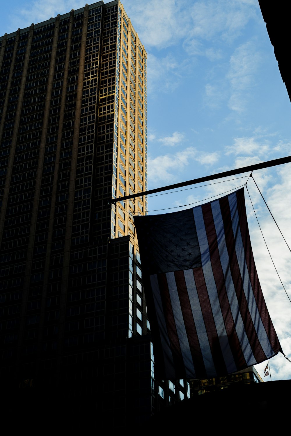 an american flag hanging from a street light in front of a tall building