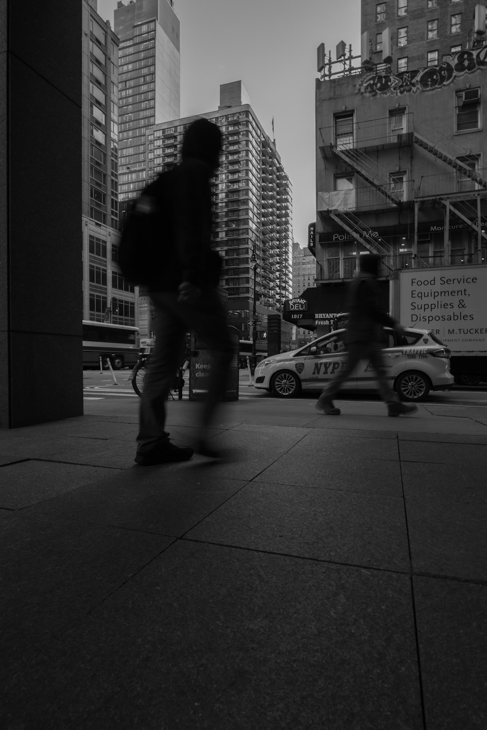 a couple of people walking down a street next to tall buildings