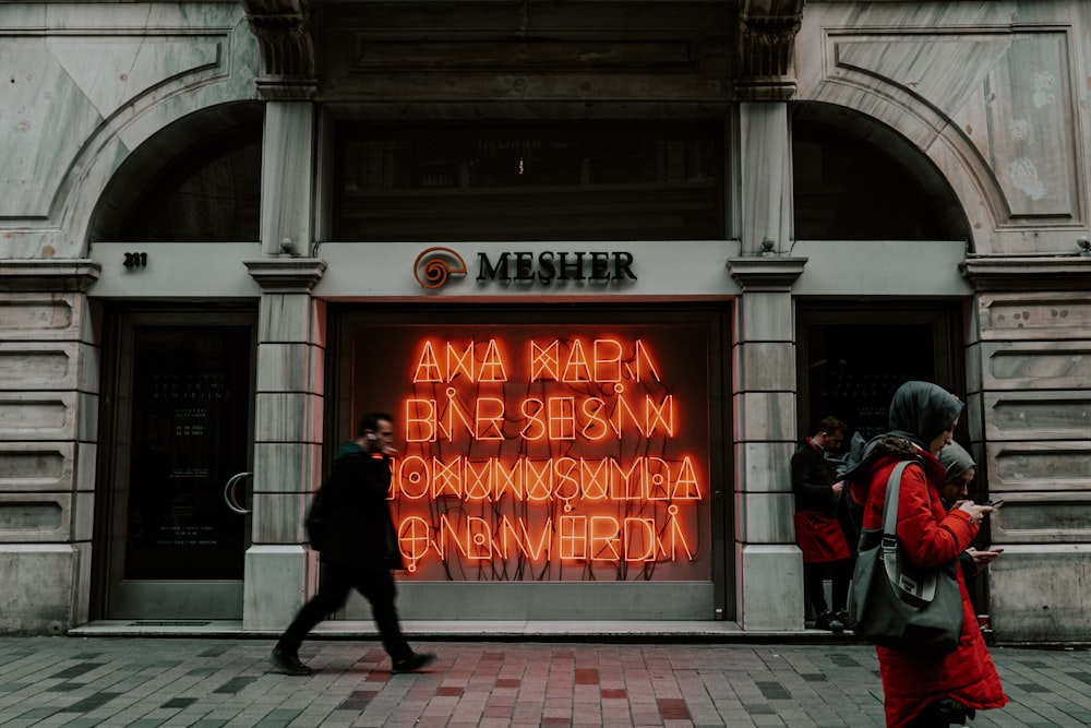 a group of people walking past a neon sign