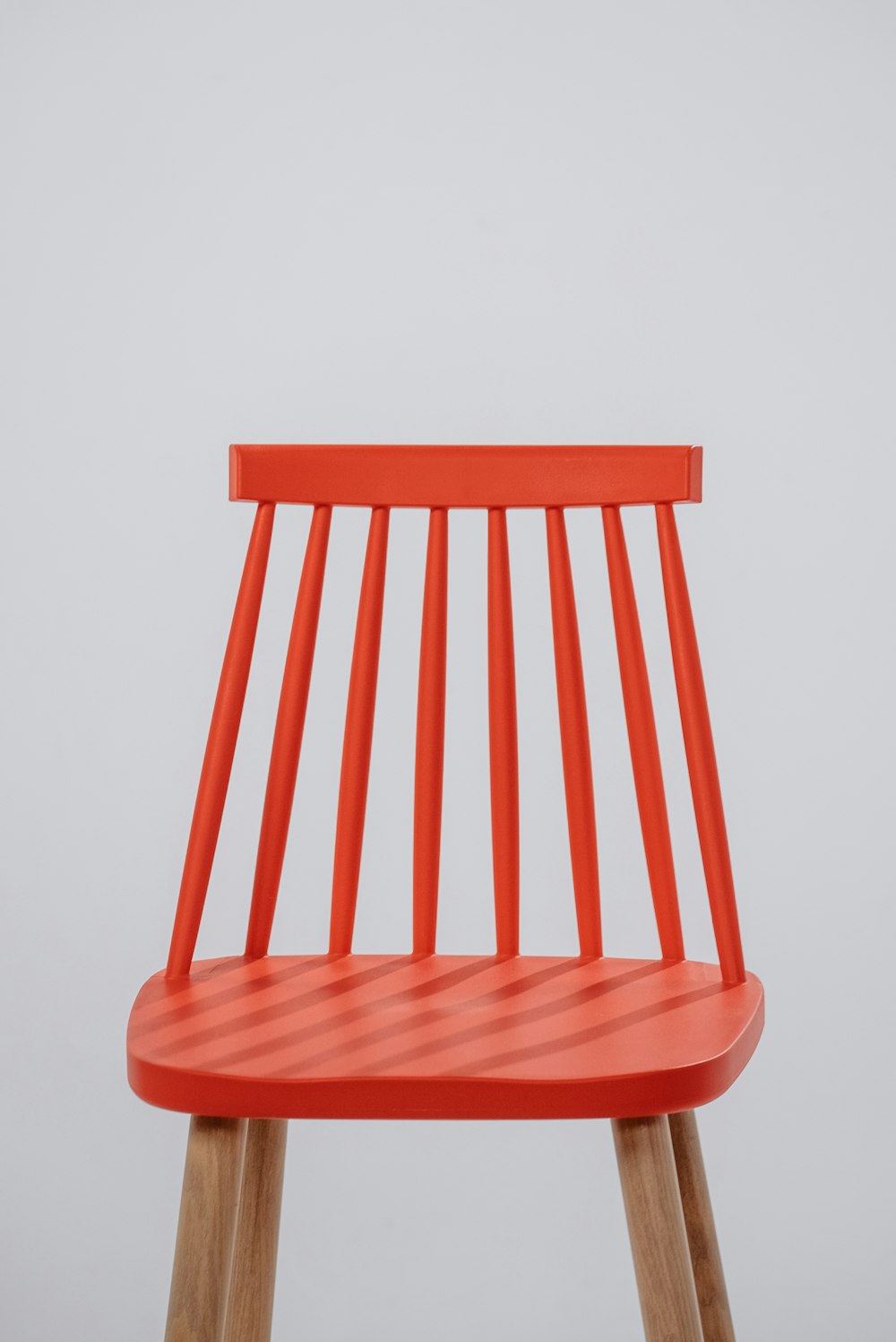 a red chair with wooden legs on a white background