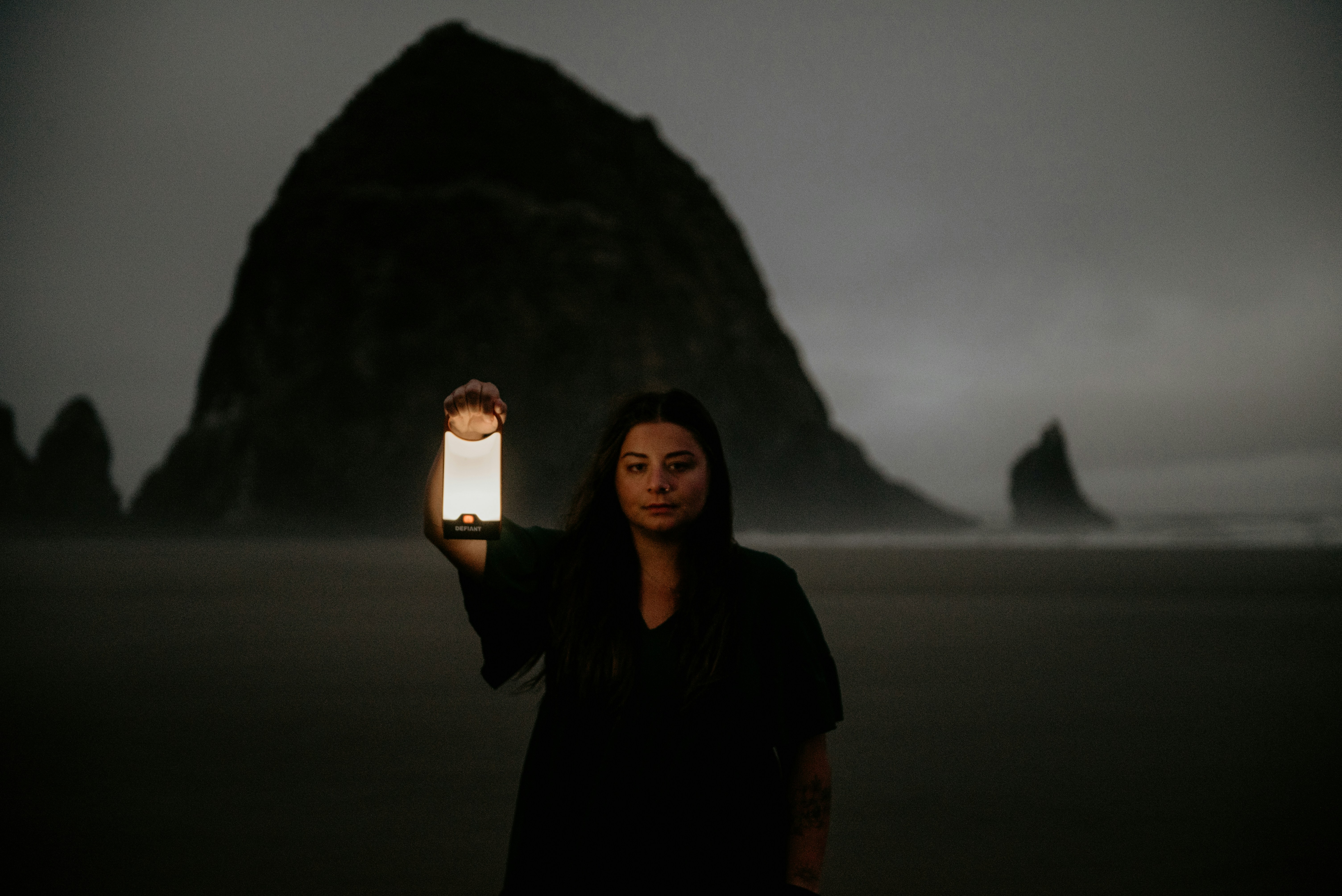 a woman holding a lit candle in front of a mountain