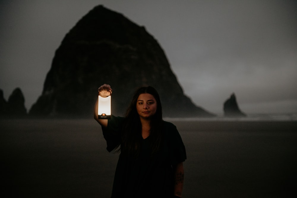 a woman holding a lit candle in front of a mountain