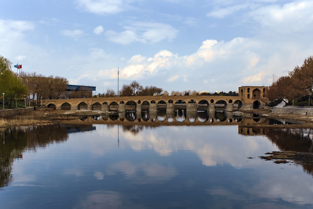 a bridge over a body of water under a cloudy blue sky