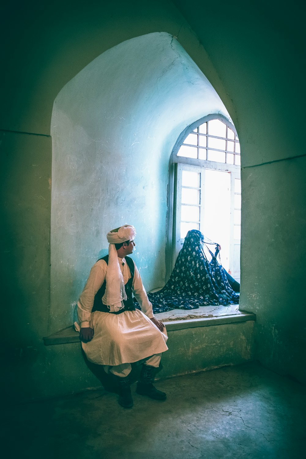 a woman sitting on a window sill next to a bag