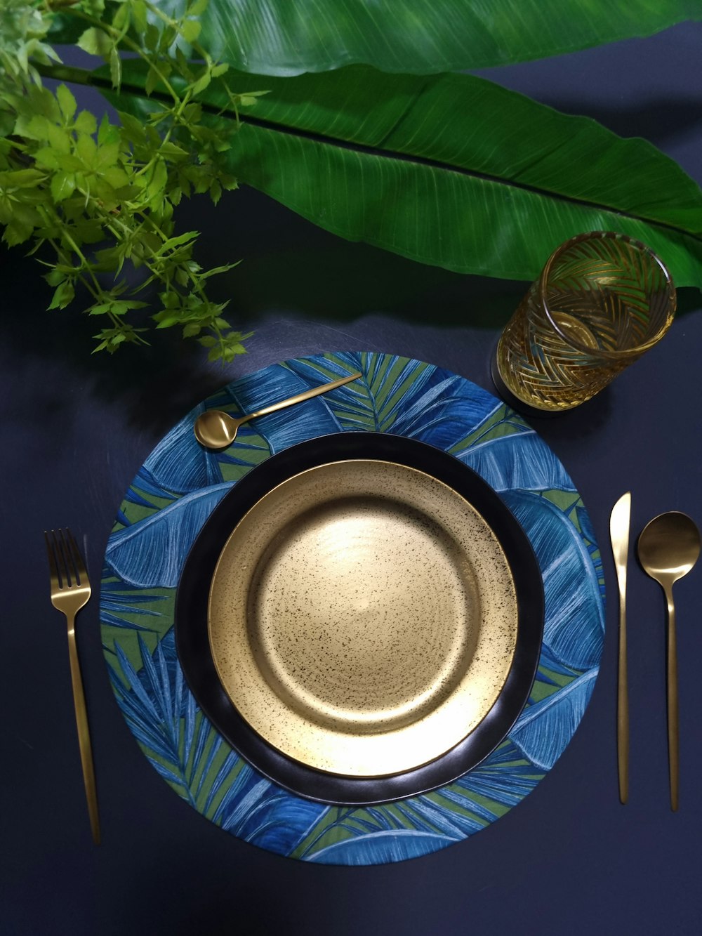 a blue plate with a gold rim sits on a blue table