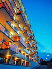 A luxury apartment tower overlooking a vibrant cityscape at dusk.