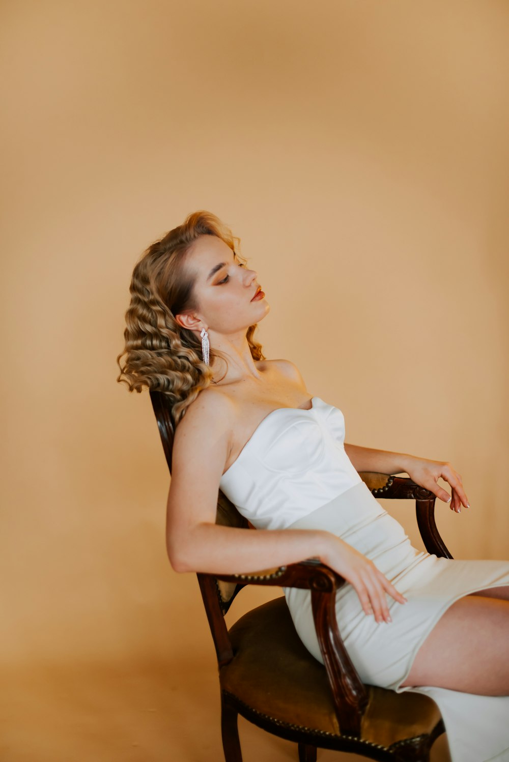 a woman in a white dress sitting in a chair