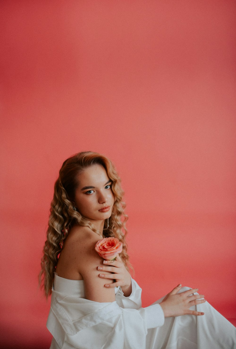a woman in a white dress holding a rose