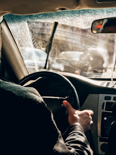 Student practicing driving behind the wheel with a patient instructor guiding beside.