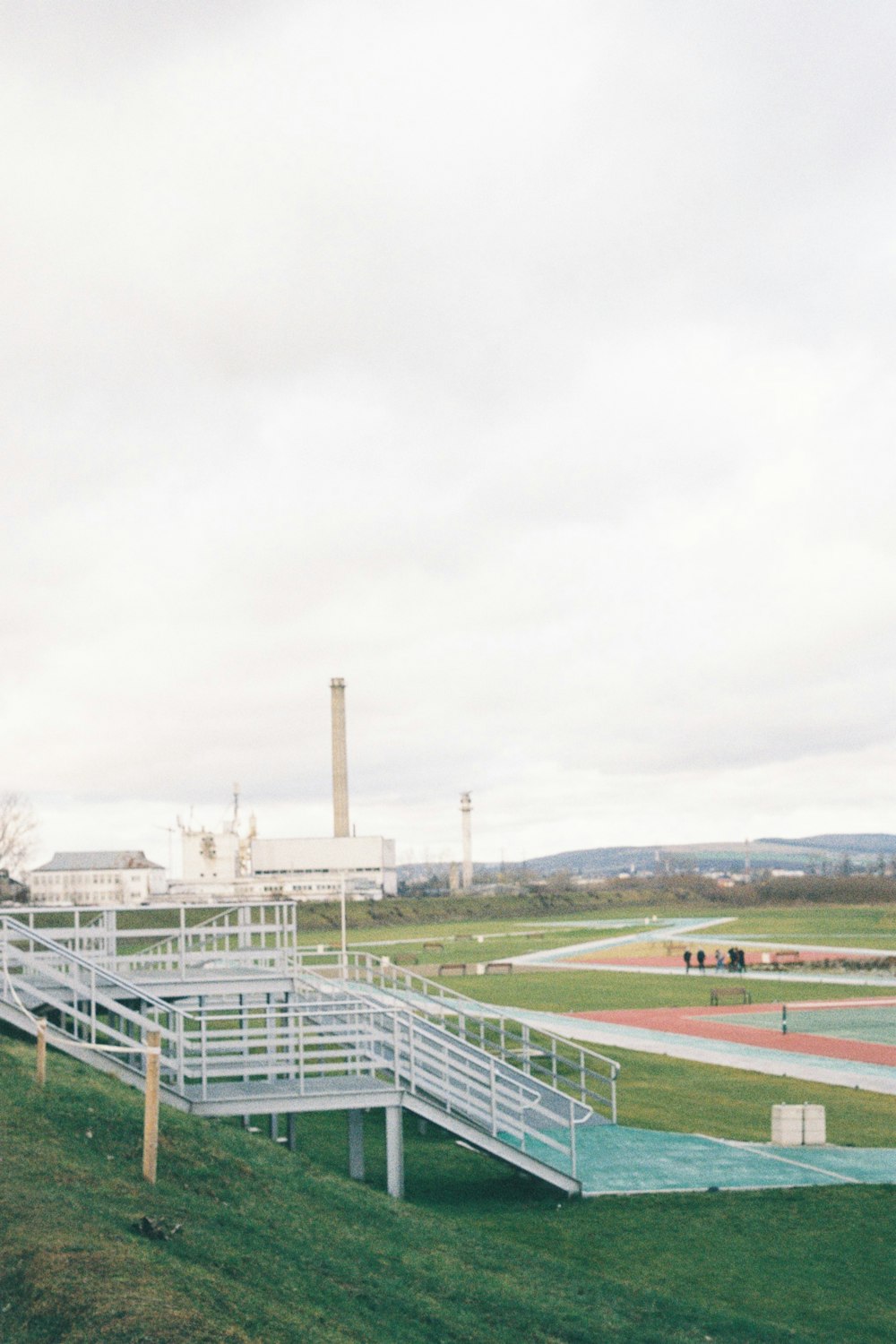 a large grassy field with a white bridge