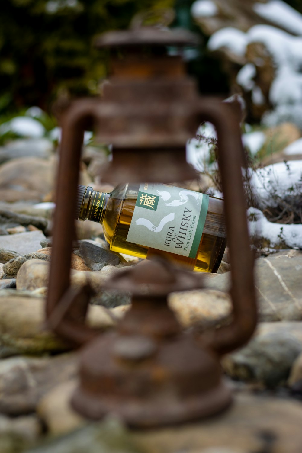 a bottle of wine sitting on top of a rock covered ground