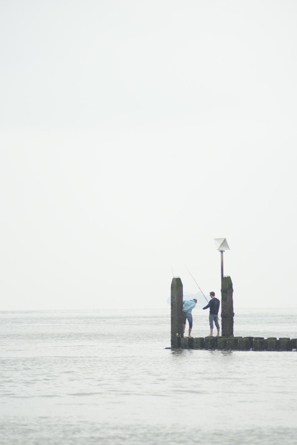 a couple of people standing on top of a pier