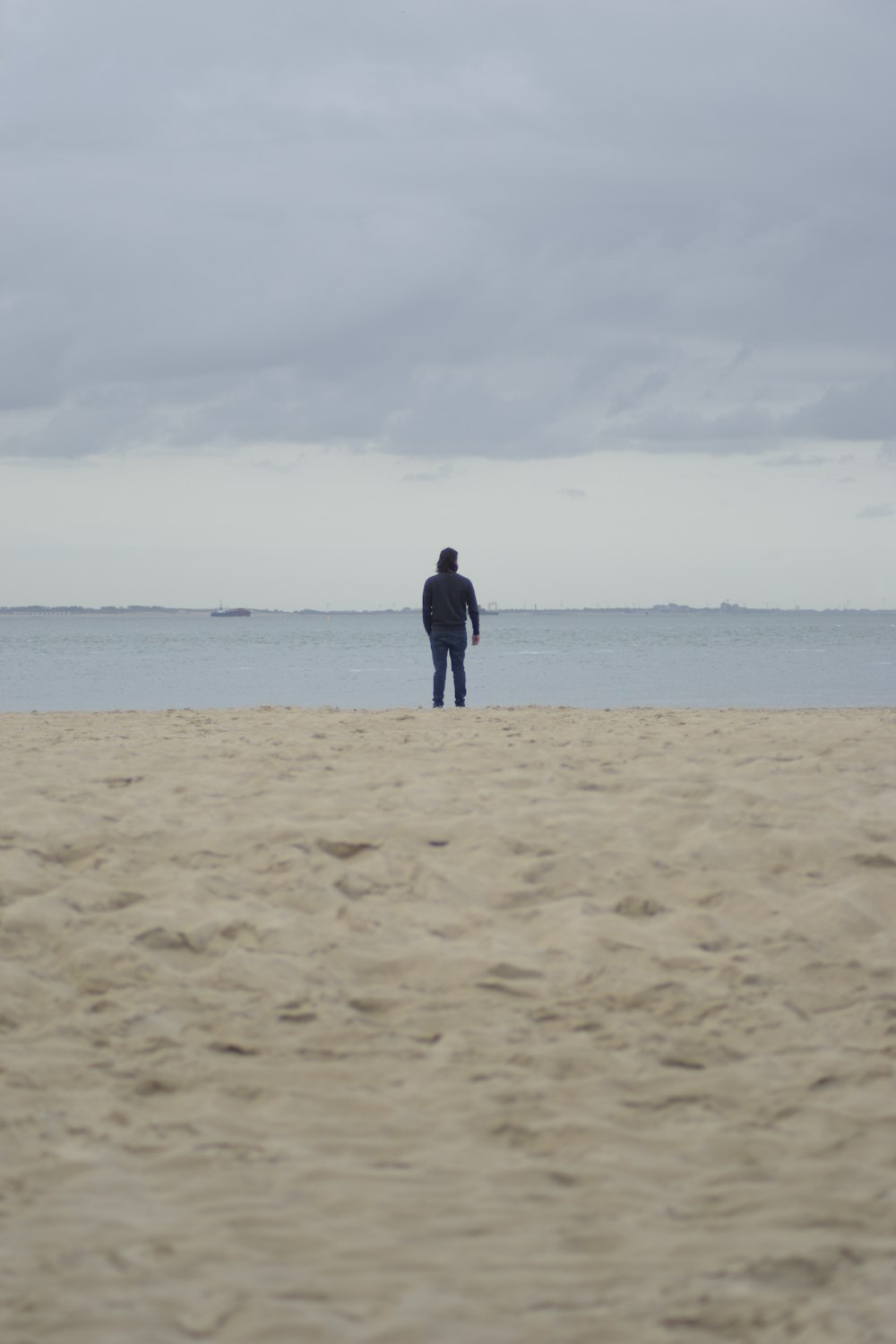 Un uomo in piedi sulla cima di una spiaggia sabbiosa