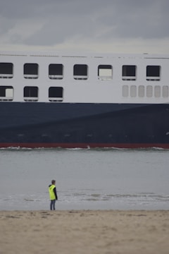 a man standing on a beach next to a large ship