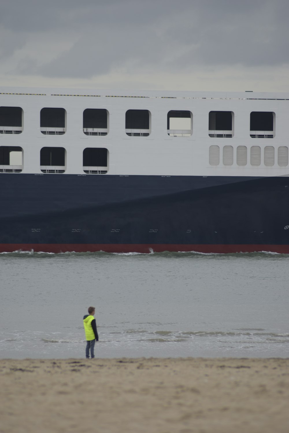 Un uomo in piedi su una spiaggia accanto a una grande nave
