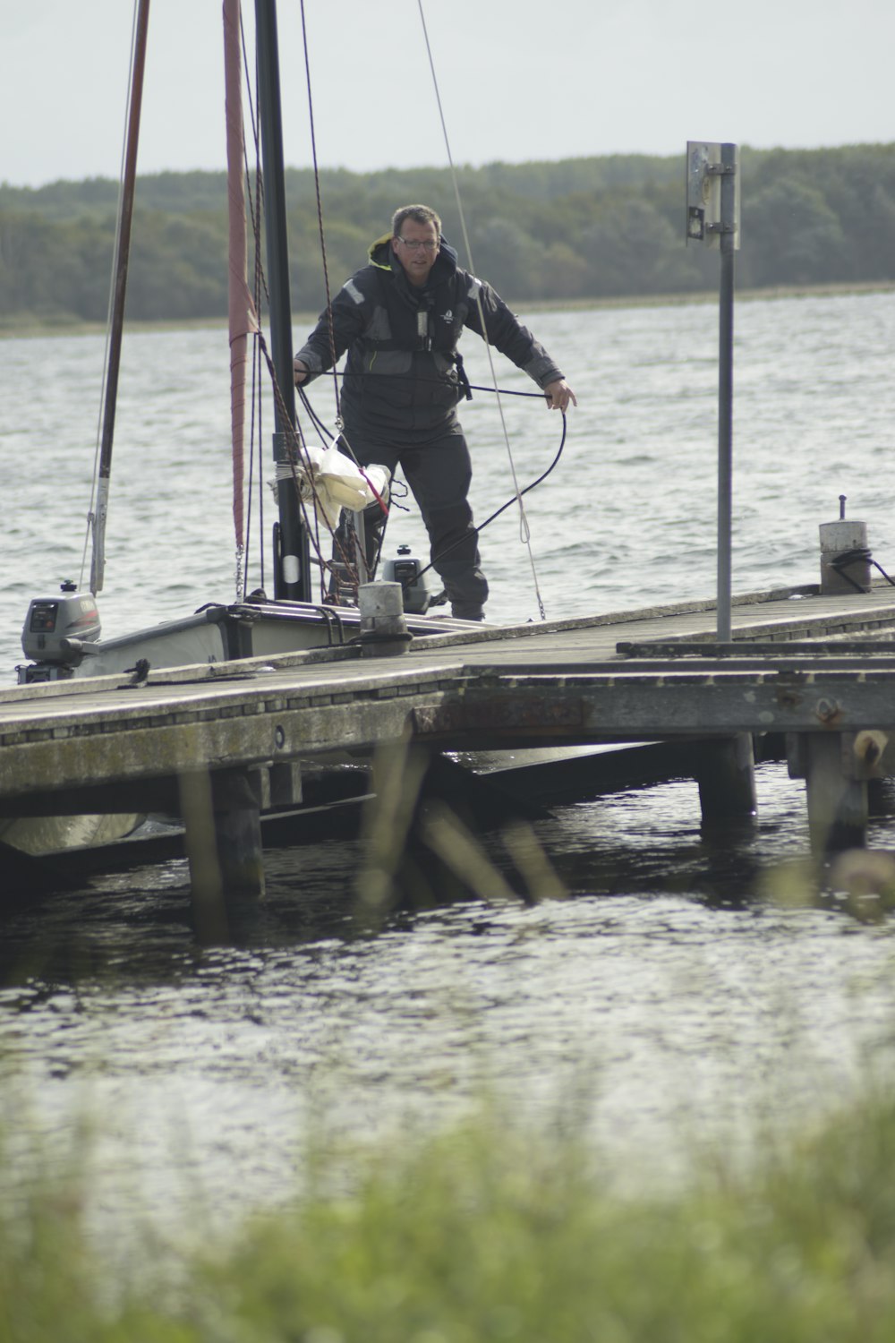 Ein Mann steht auf einem Dock neben einem Segelboot