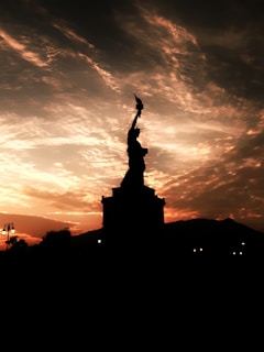 Silhouettes of Michelangelo's David statue against a twilight sky in Rome.