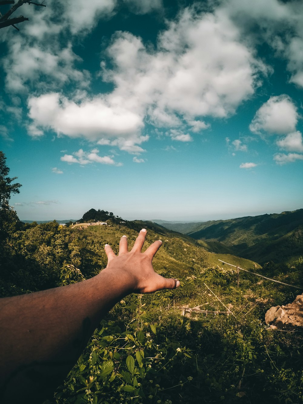 a hand reaching up into the sky with a mountain in the background