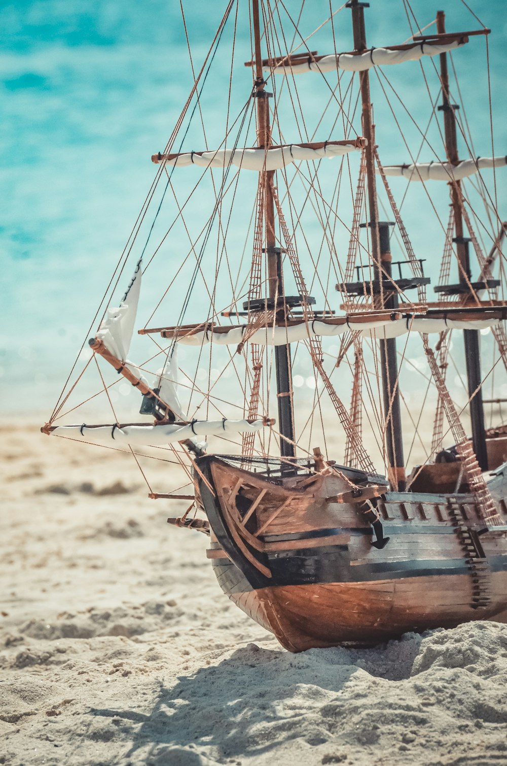 a wooden model of a sailing ship on the beach