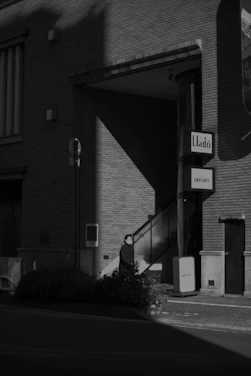 A stark black-and-white photo of a dimly lit urban alleyway, evoking the raw edge of underground scenes.