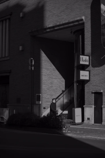 A stark black-and-white photo of a dimly lit urban alleyway, evoking the raw edge of underground scenes.